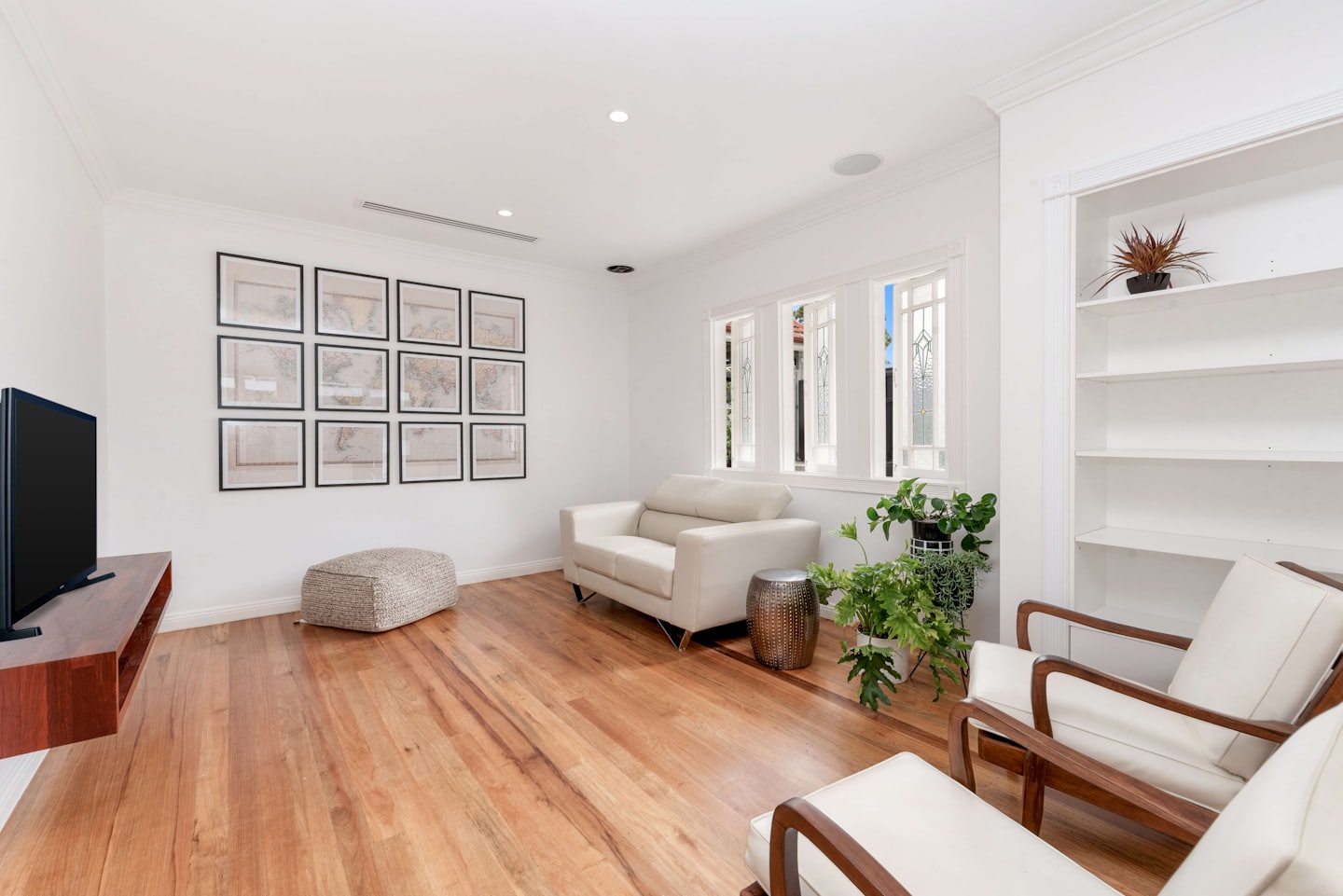 Moderne woonkamer met crèmekleurige bank, fauteuils en landkaartprints.