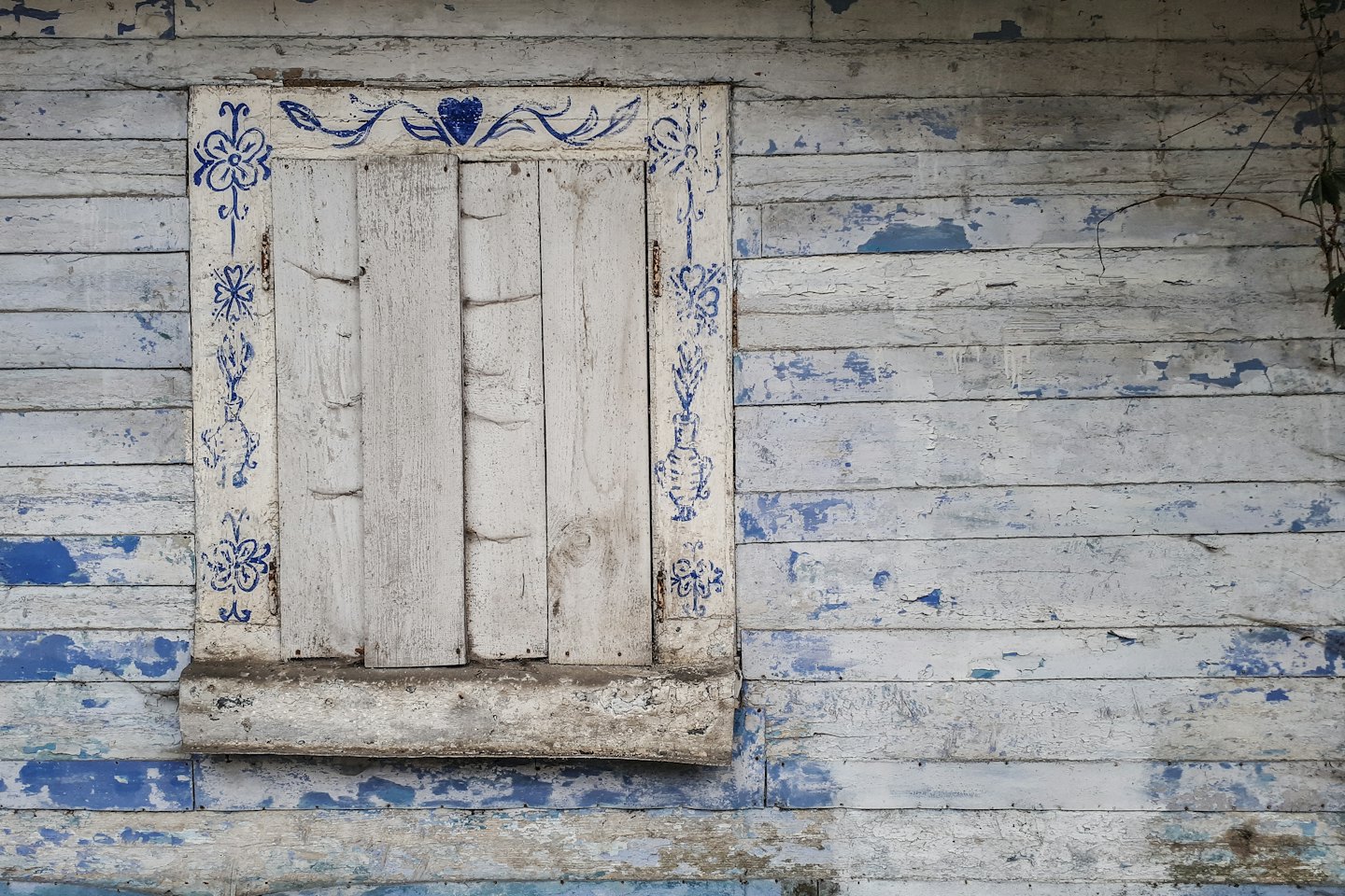Witte en blauwe geschilderde houten muur met decoratief raam.