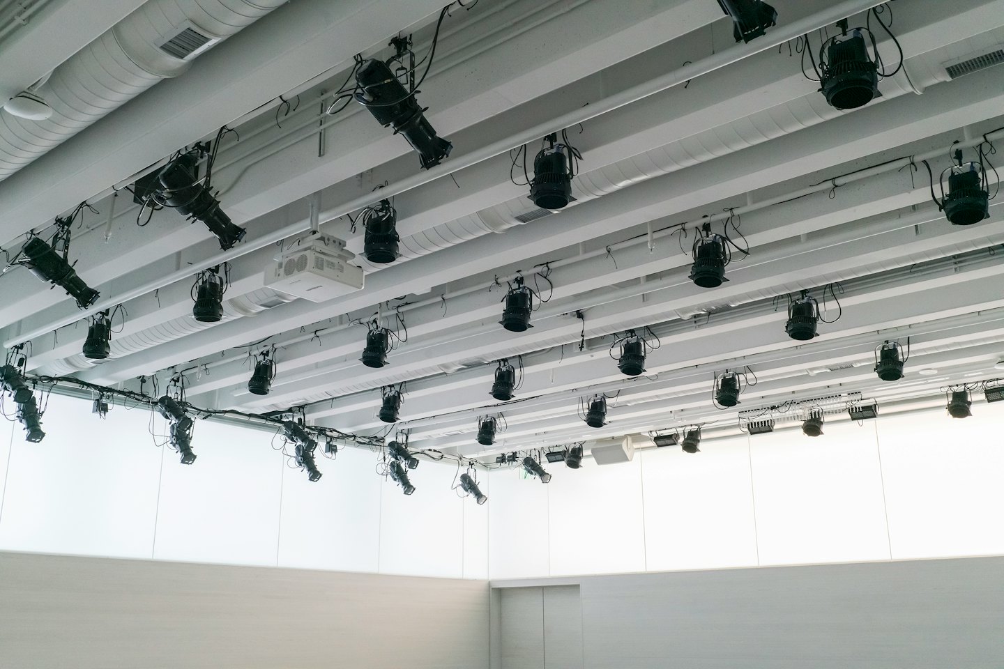 Wit plafond met zwarte spots en ventilatie die een patroon vormen.