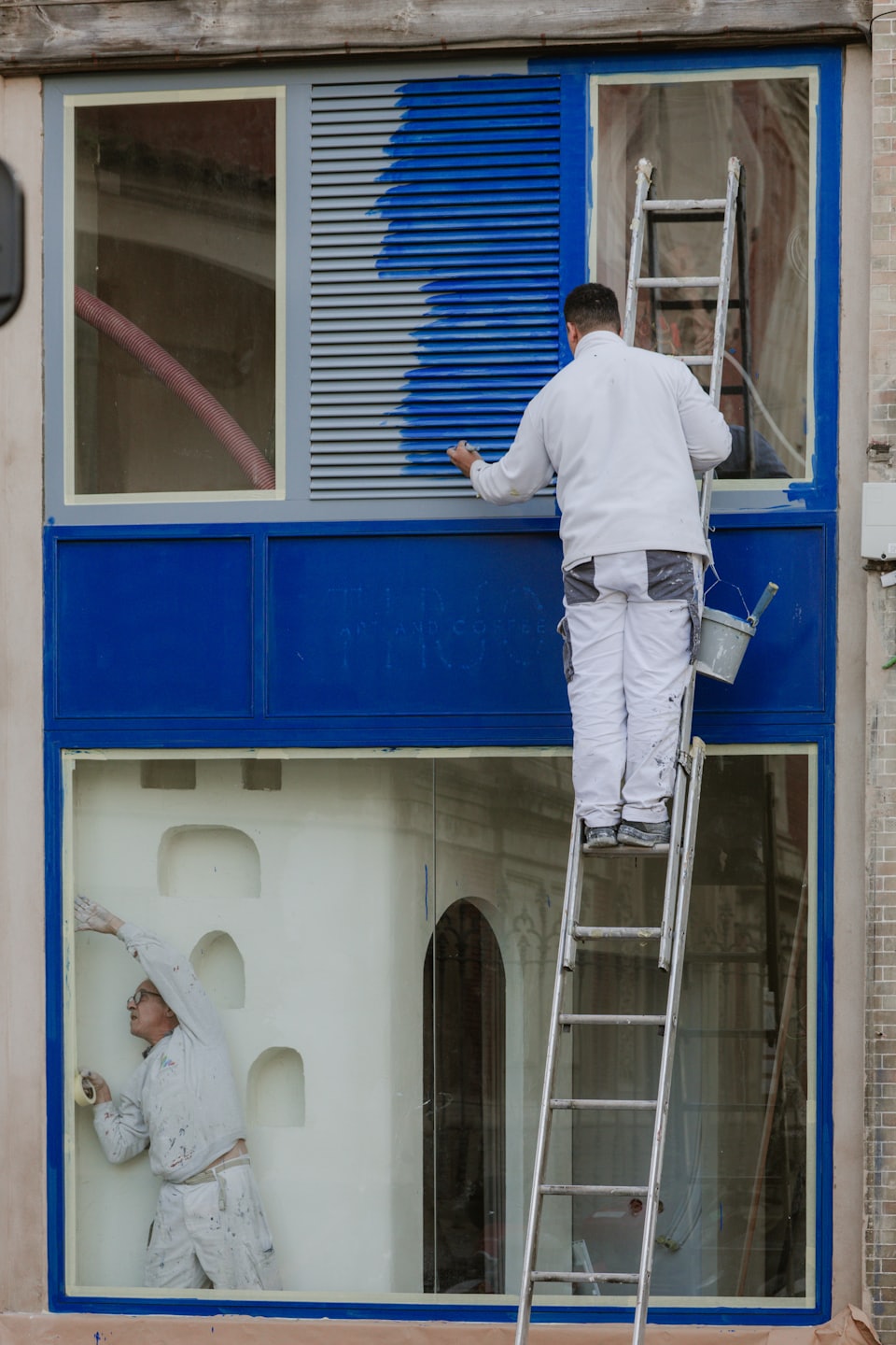 Schilders die aan een gevel werken tijdens een renovatie.